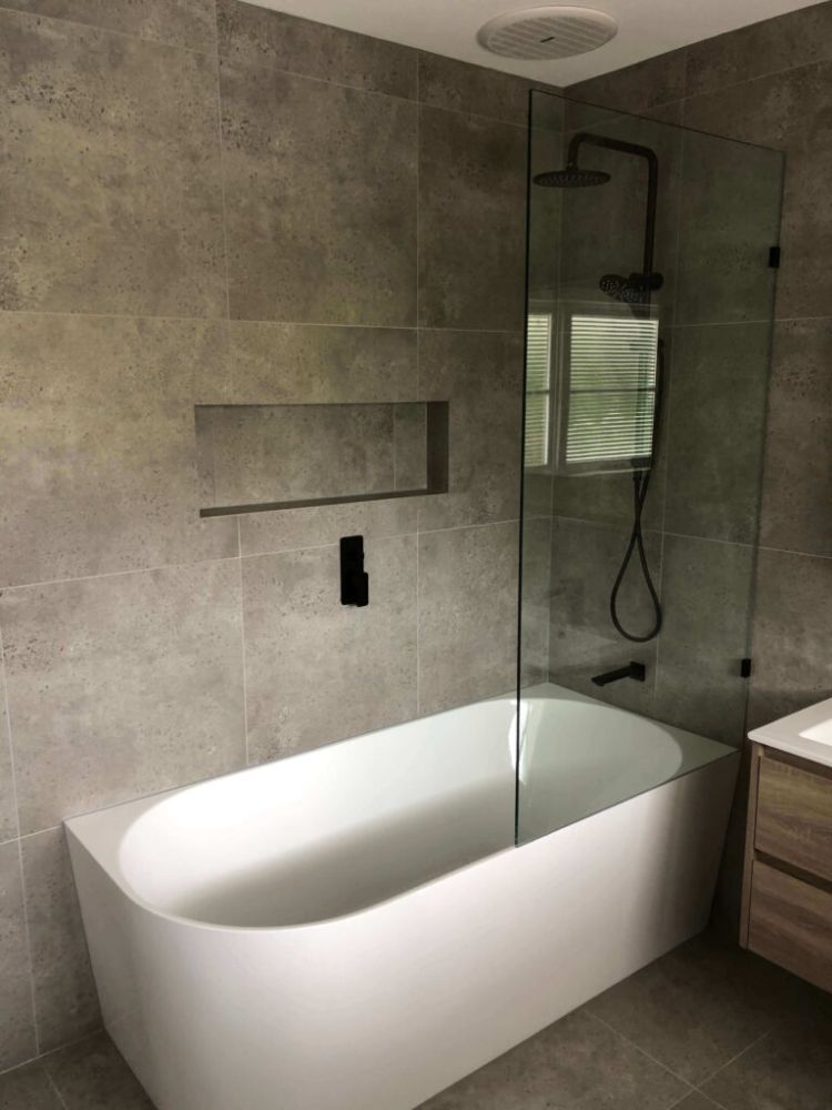 White curved bath with a glass shower screen and black fittings